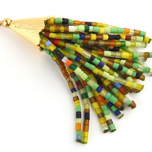 May include: A decorative tassel pendant featuring a gold-toned metal cap with a textured surface and a jump ring. The tassel consists of multiple strands of small, cylindrical glass beads in various shades of green, yellow, blue, and orange.