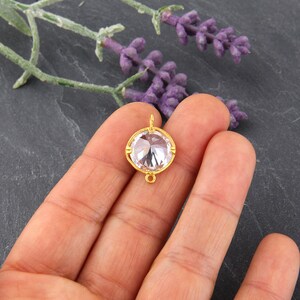 May include: Gold-toned pendant with a clear round crystal. The pendant has a loop at the top for attaching to a chain.