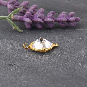 May include: Gold-toned connector with a clear crystal in the shape of a pyramid. The connector has a loop on each side.