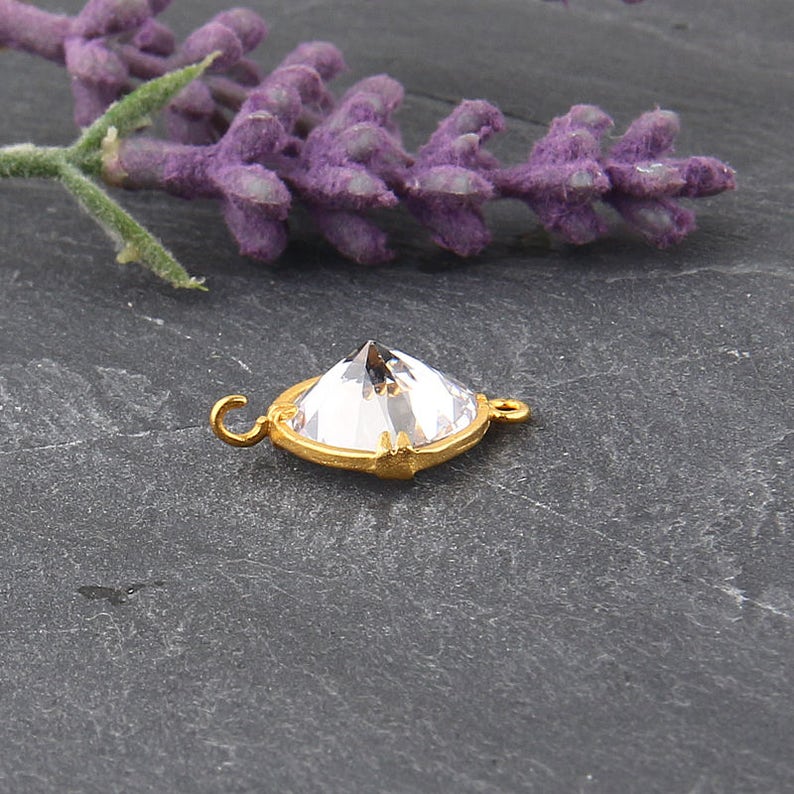 May include: Gold-toned connector with a clear crystal in the shape of a pyramid. The connector has a loop on each side.