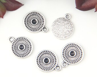 Peut inclure: Plusieurs breloques en métal argenté. Les breloques circulaires présentent un motif de soleil détaillé autour d'une perle noire centrale. Chaque breloque a une petite boucle pour l'attacher à un bijou. Une breloque a un dos texturé.