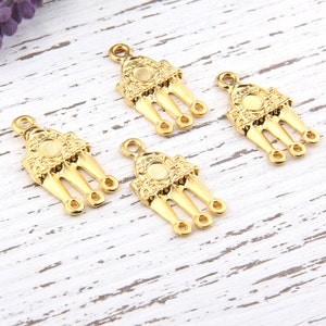 Puede incluir: Cuatro colgantes de metal de color dorado con un diseño decorativo y tres lazos. Cada colgante tiene un centro circular con una superficie texturizada en relieve.