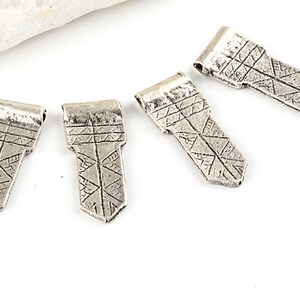 May include: Four silver-toned metal pendant charms with a geometric design. Each charm has a pointed tip and a loop at the top for attaching to a necklace or bracelet.