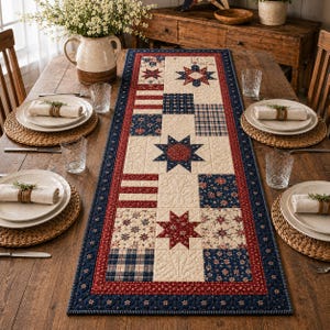 May include: A rectangular quilted table runner featuring a patchwork design of red, white, and blue fabric squares. The pattern includes star motifs, floral prints, and plaid squares, all bordered by a dark blue frame with a thin red trim.
