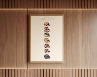 Puede incluir: Un póster vertical enmarcado que presenta el texto LEWIS HAMILTON en la parte superior, seguido de una columna de siete cascos de carreras distintos con varios colores y diseños, sobre un fondo blanco roto en un marco de madera clara.