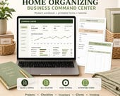 A laptop displaying a "Home Organizing Business Command Center" dashboard, with a pen, a green notebook, and various paper forms and file folders arranged around it.