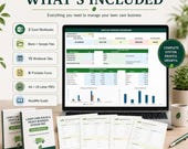 A laptop displays a monthly business dashboard, with printed covers for a lawn care business system and various forms, all on a light wooden surface.