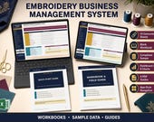 Two laptops display the "Embroidery Business Management System" interface, surrounded by spools of thread, scissors, and printed guidebooks.