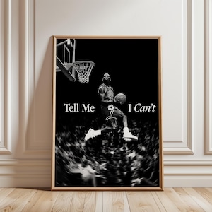 May include: A black and white vertical poster featuring a basketball player in mid-air jumping towards a hoop while holding a basketball. The text "Tell Me I Can't" is printed in white serif font across the centre of the image over a blurred crowd.