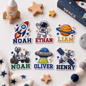 Può includere: Sei toppe ricamate a tema spaziale raffiguranti un razzo, un astronauta, un pianeta, un rover, un UFO e un satellite. Ogni toppa include un nome personalizzato: Noah, Ethan, Liam, Noah, Oliver e Henry, decorate con piccole stelle.