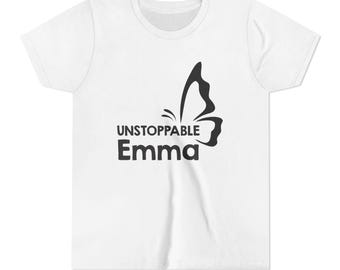 Peut inclure: Un t-shirt blanc à manches courtes avec une impression graphique noire sur le devant. Le motif se compose d'une silhouette de papillon stylisée placée au-dessus du texte UNSTOPPABLE Emma, écrit dans une police noire grasse sans empattement.