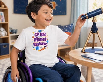 May include: A white short-sleeved t-shirt featuring a colourful graphic of planets, stars, and a rocket ship with the text CP Kid, Planet Explorer in purple and blue letters. The shirt is worn with dark blue jeans while sitting in a wheelchair.