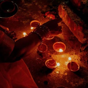 Pode incluir: Uma cole&ccedil;&atilde;o de pequenas l&acirc;mpadas de &oacute;leo redondas de terracota, conhecidas como diyas, est&atilde;o dispostas no ch&atilde;o. Cada l&acirc;mpada cont&eacute;m um pavio aceso que emite um brilho dourado quente, iluminando a &aacute;rea com uma luz suave e cintilante.