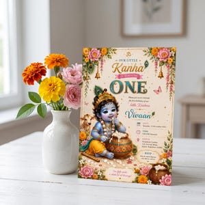 May include: A rectangular birthday invitation card featuring an illustration of a blue-skinned child deity with a peacock feather, a pot of butter, and floral borders. The text reads Our Little Kanha Is Turning One, Vivaan, and event details.