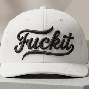Pode incluir: Um boné de beisebol branco com a palavra "Fuckit" bordada em letras pretas em relevo nos painéis frontais. O boné tem uma copa estruturada, aba curva e um design clássico de seis painéis com costuras brancas a condizer.