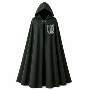 Puede incluir: Una capa con capucha de color verde oscuro que presenta un cierre de metal plateado en el cuello. La prenda muestra un emblema bordado prominente en el pecho izquierdo, que representa un escudo con dos alas superpuestas en hilos blanco, gris y negro.