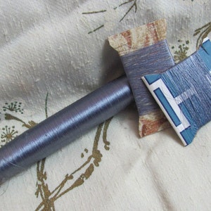 May include: A spool of blue thread with a cardboard spool and two smaller spools of blue thread.