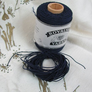 May include: A spool of dark blue thread with a white label that reads "Royalsun Yarns".