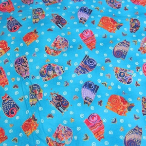 May include: A turquoise fabric with a repeating pattern of colourful cats. The cats are stylised and have a whimsical design. The background is a solid turquoise colour with white swirls.