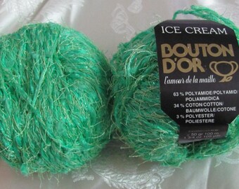 May include: Two skeins of green yarn with gold flecks. The yarn is labeled "ICE CREAM BOUTON D'OR l'amour de la maille" and lists the yarn composition as 63% polyamide, 34% cotton, and 3% polyester.