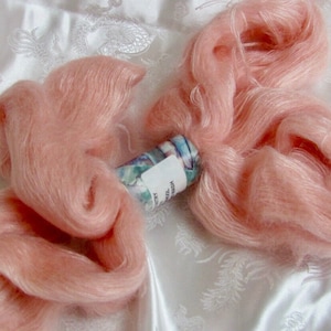 K&ouml;nnte beinhalten: Ein Kn&auml;uel weiches, pfirsichfarbenes Garn, perfekt zum Stricken oder H&auml;keln. Das Garn wird auf einem wei&szlig;en Hintergrund gezeigt.