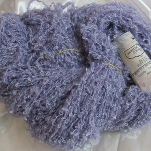 Puede incluir: Un ovillo de hilo morado con una etiqueta blanca que dice "Newton County Crafts, Silk Puffs, 0.23 oz, 54-57 yds, Made in America".