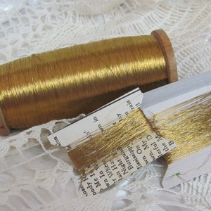 Könnte beinhalten: Eine Spule mit goldenem Metallic-Garn, das auf einer Holzspule aufgewickelt ist. Das Garn ist auch auf einer Karte mit dem Text "Bay, My Wonderful D, train, il, the M, B" abgebildet.