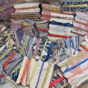May include: Assortment of colorful embroidery floss spools on small, patterned cards. The floss is arranged in a variety of colors, including gold, silver, blue, red, and orange.