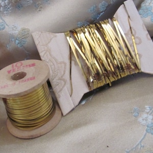 May include: A spool of gold metallic thread, wound around a wooden spool with the text "10 VERITABLE MADE IN FRANCE".