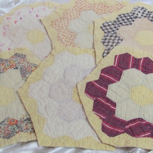 May include: A collection of nine yellow fabric squares with different floral patterns. Each square features a central flower design with a yellow center and a variety of colors and textures.