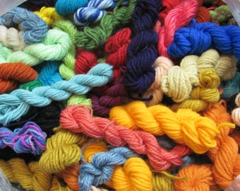 May include: A vibrant assortment of colorful yarn skeins in various shades, including blue, green, red, yellow, and orange. The image showcases a variety of textures and thicknesses, perfect for knitting, crocheting, or other fiber art projects.