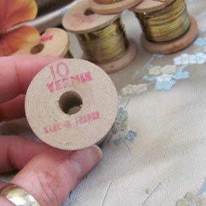 May include: A wooden spool of gold thread with the text "10 VERMEIL" and "MADE IN FRANCE" printed on it.