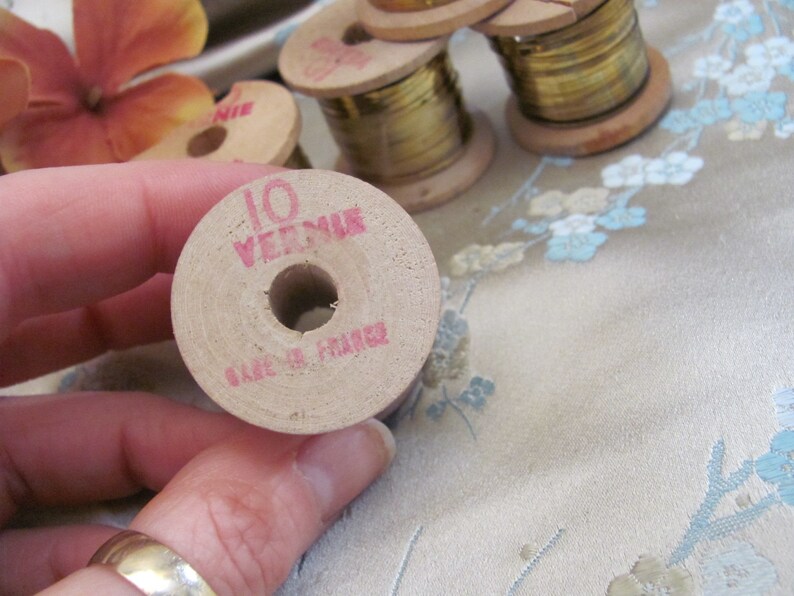May include: A wooden spool of gold thread with the text "10 VERMEIL" and "MADE IN FRANCE" printed on it.