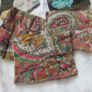 K&ouml;nnte beinhalten: Zwei Stoffst&uuml;cke mit einem Paisley-Muster in Braun-, Gr&uuml;n-, Rosa- und Wei&szlig;t&ouml;nen. Der Stoff ist gesteppt und hat eine leicht strukturierte Oberfl&auml;che.