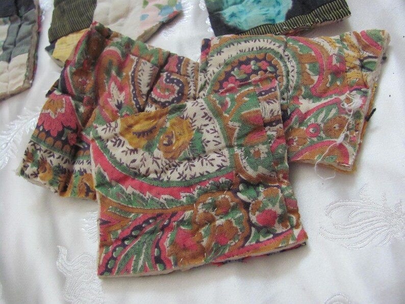K&ouml;nnte beinhalten: Zwei Stoffst&uuml;cke mit einem Paisley-Muster in Braun-, Gr&uuml;n-, Rosa- und Wei&szlig;t&ouml;nen. Der Stoff ist gesteppt und hat eine leicht strukturierte Oberfl&auml;che.