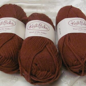 Può includere: Tre gomitoli di lana marrone etichettati "Knit Picks Wool of the Andes" con un'etichetta bianca.