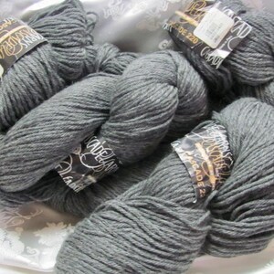 Op de afbeelding: Vier bollen grijs garen met zwarte etiketten met de tekst "Cascade 220 Superwash" en "Gemaakt in Canada".