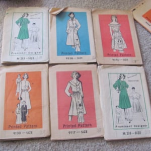 May include: Six vintage sewing patterns featuring women's clothing designs. The patterns are printed on white paper with a colorful background. The patterns include a dress with a Peter Pan collar, a dress with a scoop neck, a dress with a V-neck, a dress with a boat neck, a dress with a scoop neck, and a coat with a shawl collar. The patterns are labeled with the pattern number and size.