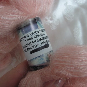 K&ouml;nnte beinhalten: Ein Kn&auml;uel blassrosa Mohairgarn mit einem Etikett mit der Aufschrift "Enton's Yarn Count 1-800-899-9116 Italian Mohair/Wool 1 oz, 500 yds, Hand Washed"