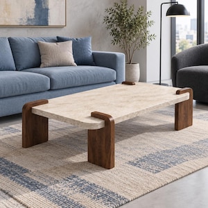 Peut inclure: Une table basse rectangulaire dotée d'un plateau beige clair à l'aspect pierre texturée avec des coins arrondis. La table est soutenue par quatre pieds en bois brun foncé qui s'enroulent sur les bords du plateau, créant un contraste marqué.