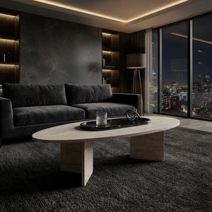 May include: An oval coffee table with a light wood grain finish and two vertical slab legs. The table surface holds a black oval tray containing a clear glass tumbler and a dark, curved decorative object, set against a dark interior.
