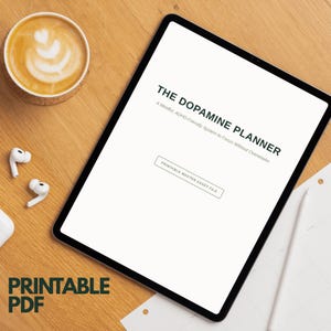 May include: A digital tablet displaying a white screen with the black text THE DOPAMINE PLANNER, A Mindful, ADHD-Friendly System to Focus Without Overwhelm, and a box labeled PRINTABLE MASTER ASSET FILE. The text PRINTABLE PDF is visible below.