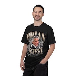May include: A black short-sleeve t-shirt featuring a graphic print of Brian Steel. The design includes multiple portraits of the individual in a suit and tie, with the text BRIAN STEEL in large metallic-toned letters and ATTORNEY AT LAW below.