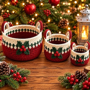 May include: A set of three round crochet baskets in descending sizes, featuring a deep red base, a cream-coloured upper section with a green dotted border, and a decorative holly leaf and red berry applique on the front of each basket.