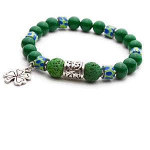 May include: A green beaded bracelet with a silver clover charm. The bracelet features green, blue, and white patterned beads, along with textured green beads and a decorative silver tube. A charming accessory.