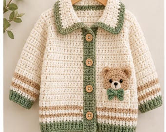 May include: A cream-colored crochet cardigan featuring a green collar, green button placket with four wooden buttons, and green cuffs. The garment includes a pocket on the front containing a small crocheted bear with a green bow tie.