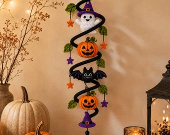 May include: A vertical crochet wall hanging featuring a black spiral structure decorated with a white ghost in a purple hat, two orange jack-o'-lanterns, a black bat, green leaves, and small orange and purple stars, finished with a purple tassel.