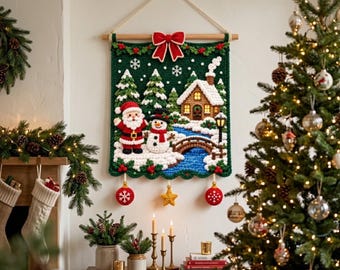 May include: A rectangular crochet wall hanging featuring a winter scene with Santa Claus, a snowman, a snow-covered house, and pine trees on a dark green background. The piece is suspended from a wooden rod with a red bow and three hanging ornaments.
