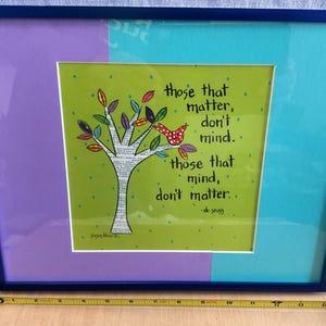 May include: Framed art print with a blue frame, featuring a quote by Dr. Seuss: "Those that matter, don't mind. Those that mind, don't matter." The artwork includes a tree with colorful leaves and a red bird.