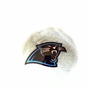 May include: A circular patch of shimmering silver glitter featuring a black and blue Carolina Panthers logo. The graphic depicts a stylized panther head in profile, facing right, with sharp white teeth and whiskers outlined in bold black and blue.